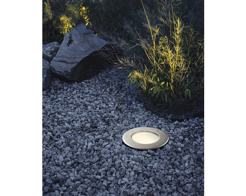 Spot encastrable au sol dans un jardin entre des graviers et des plantes