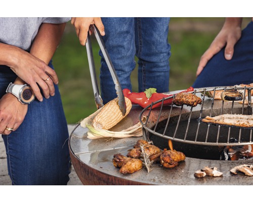 Familie grilliert Mais und Gemüse auf einem runden Grill