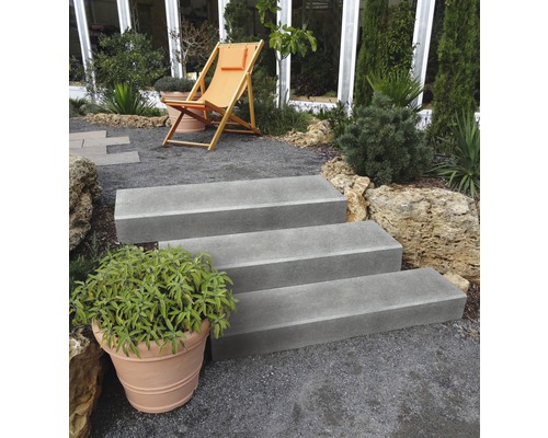 Escalier extérieur avec trois marches dans un jardin avec un chemin de gravier et une chaise longue