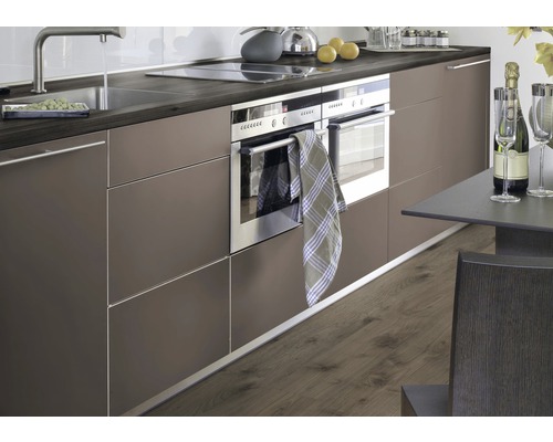 Cuisine moderne avec évier, plaque de cuisson, four et table à manger.