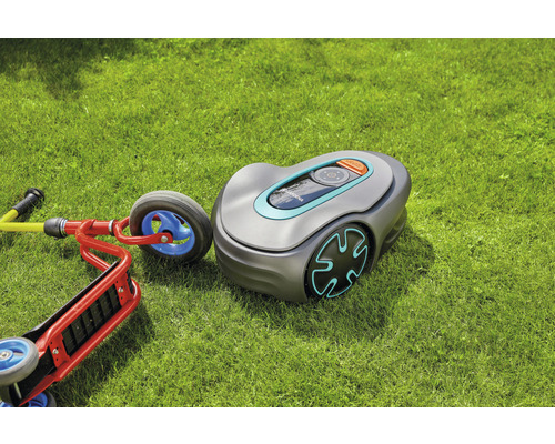 Gardena Mähroboter auf Rasen neben einem Kinderscooter