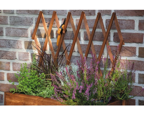 Jardinière avec treillis et sécateur devant un mur de briques