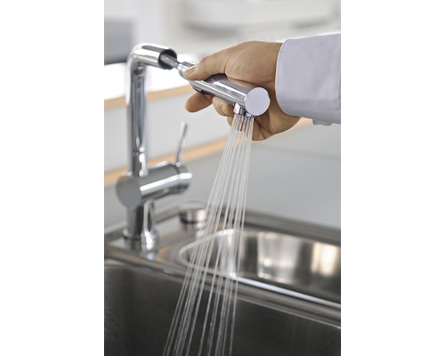 Main tenant un robinet de cuisine avec douchette au-dessus de l''évier