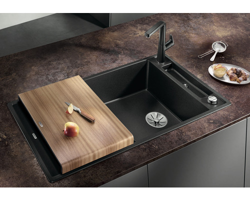 Évier en matériau composite avec planche à découper et robinetterie sur un plan de travail de cuisine