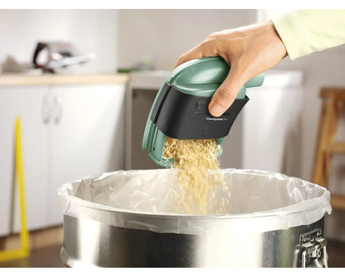 Une main vide la boîte Bosch CleanSystem au-dessus d''une poubelle