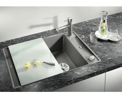 Évier de cuisine avec planche à découper et robinetterie sur un plan de travail foncé