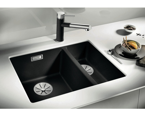 Double évier noir en matériau composite avec robinet sur un plan de travail blanc