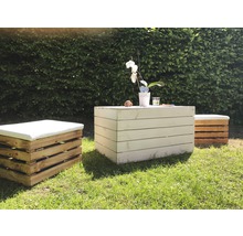 Gartenszene mit Holztisch und Hockern mit Kissen