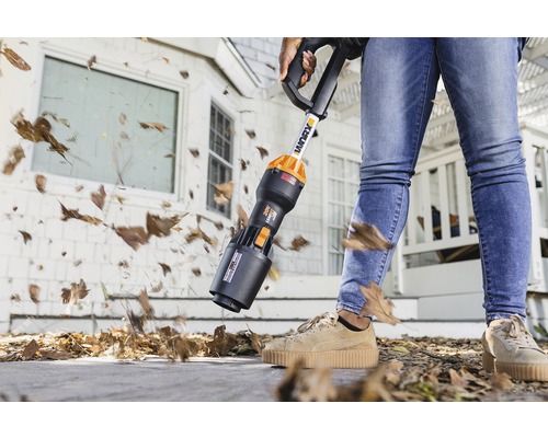 Aspirateur de feuilles à batterie en cours d''utilisation pour enlever les feuilles devant une maison.