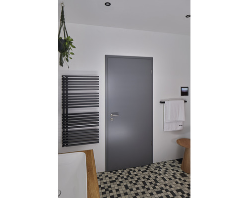 Helles Badezimmer mit Heizkörper, Tür, Handtuch und Mosaikfliesen