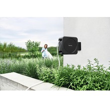 Gartenszene mit montierter Schlauchtrommel an einer Wand