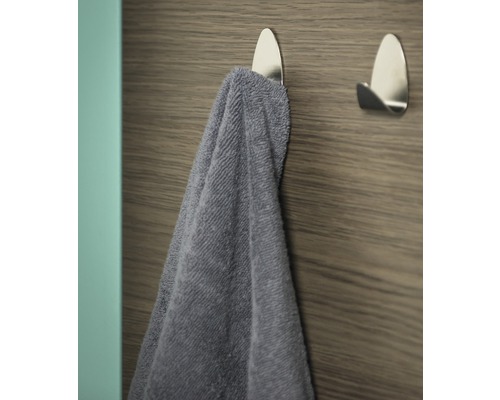 Serviette sur un crochet adhésif argenté sur un mur en bois