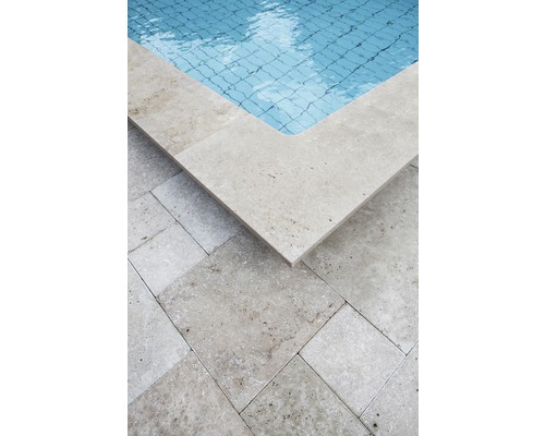 Vue détaillée d''une piscine avec margelle et dalles de sol en travertin.