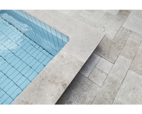 Vue détaillée d''une piscine avec bordure en pierre et sol carrelé