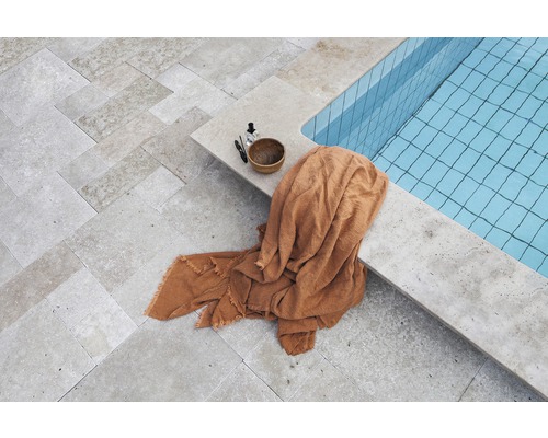 Un espace piscine avec un sol en pierre, une serviette et des produits de soin.