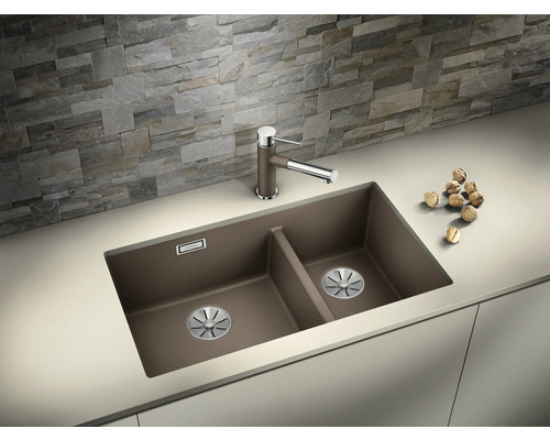 Double évier avec robinet sur un comptoir de cuisine devant un mur de pierre