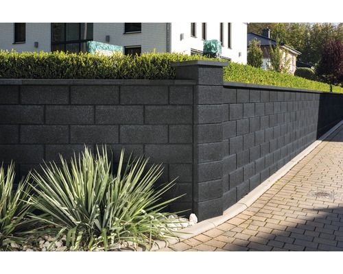 Hohe Gartenmauer aus Betonsteinen mit Pfeilerelementen und Bepflanzung