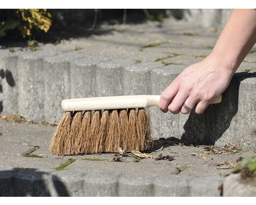 Une main balaie un escalier en pierre avec une brosse