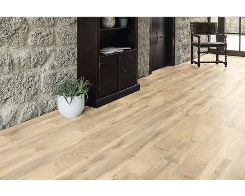 Plancher en bois clair dans une pièce avec mur en pierre, armoire en bois foncé et chaise