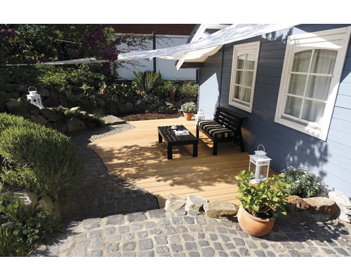 Gartenbereich mit Holzterrasse, Sitzbank und Tisch vor einem Gartenhaus