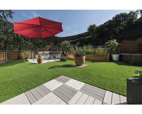 Espace extérieur aménagé avec gazon synthétique, dalles de terrasse, parasol et mobilier de jardin