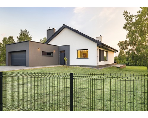Ein modernes Haus mit einem Metallzaun im Garten.