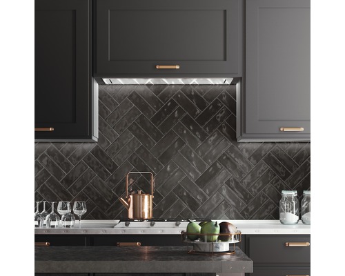 Scène de cuisine avec armoires sombres, carreaux à chevrons et ustensiles de cuisine