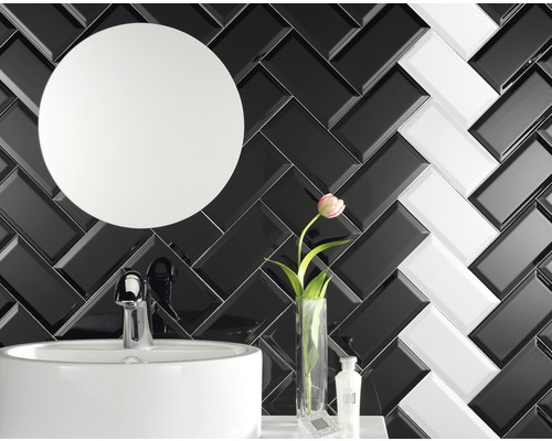 Vue de salle de bains avec lavabo, miroir rond et carrelage mural à chevrons