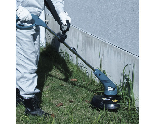 Une personne utilise un coupe-bordure dans le jardin.