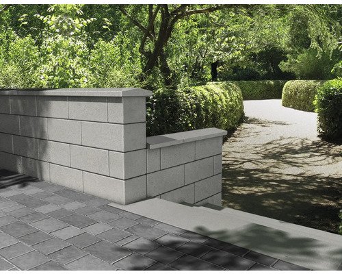 Aménagement paysager de jardin avec mur en blocs de béton et sol pavé.