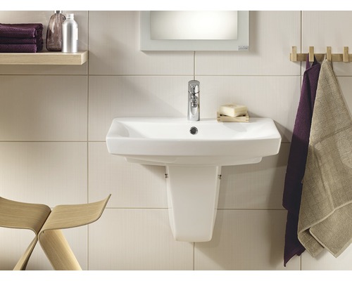 Salle de bain lumineuse avec lavabo, robinet et serviettes sur une latte en bois