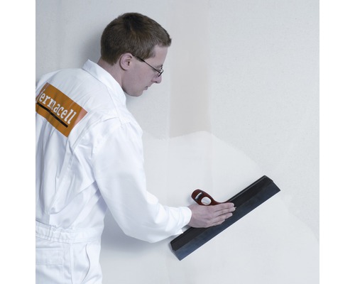 Artisan lissant un mur avec une spatule de surface