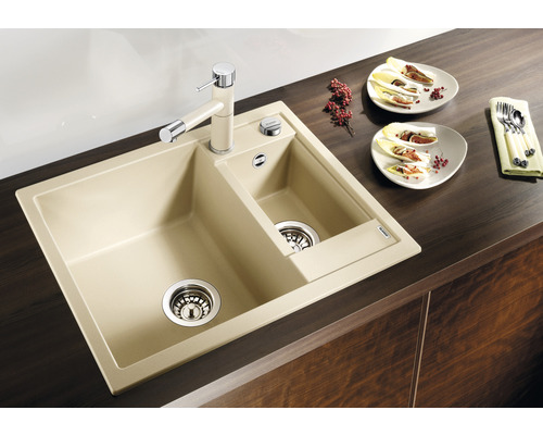 Beige Küchenspüle mit zwei Becken und Wasserhahn auf einer Arbeitsplatte.
