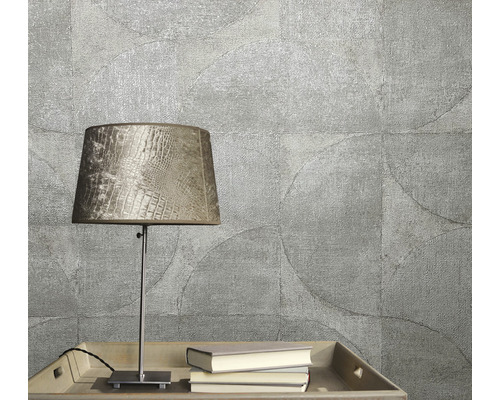 Gros plan d''un papier peint texturé à motif circulaire, complété par une lampe de table et des livres sur un plateau