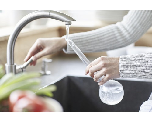 Femme remplissant une bouteille en verre d''eau au robinet