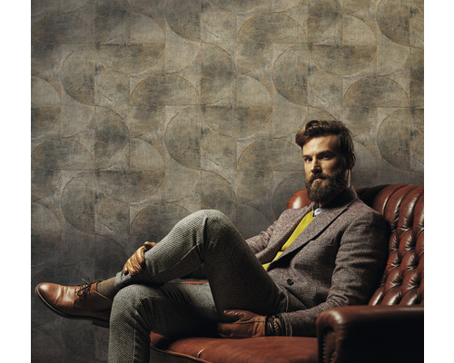 Mann sitzt vor einer Wand mit Kreis Muster Tapete auf einem Ledersofa