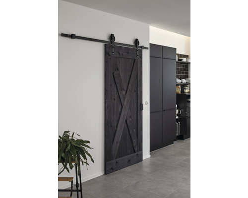 Schwarze Schiebetür im Scheunenstil mit Beschlägen vor der Wand