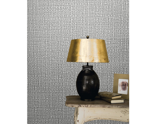 Gros plan d''un papier peint textile argenté imitant la structure textile avec une lampe sur une table