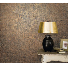 Nahaufnahme einer Wand mit einer strukturierten Tapete neben einem Tisch mit Lampe, Büchern und Fotorahmen.