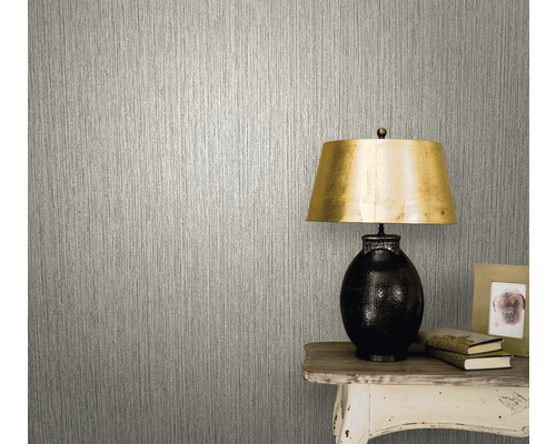 Nahaufnahme einer Wand mit einer Tapete mit vertikalem Struktureffekt neben einem Tisch mit Lampe, Büchern und einem Fotorahmen.