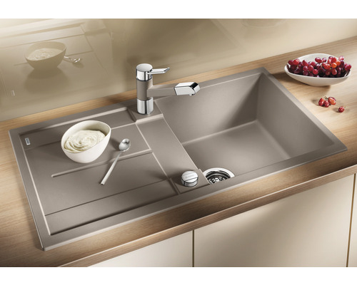 Évier avec égouttoir et robinetterie de cuisine sur un plan de travail avec des aliments.