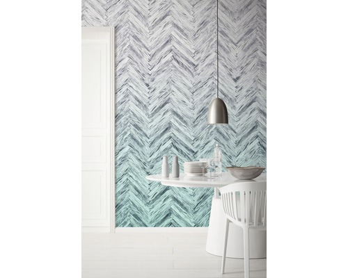 Une salle à manger avec un papier peint à chevrons, une table ronde et des chaises.