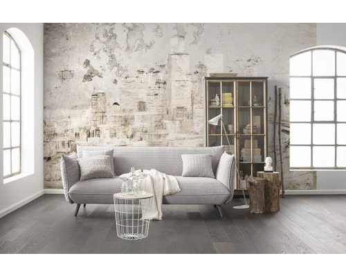 Salon avec canapé, étagère, table et décoration devant un mur avec motif de journal