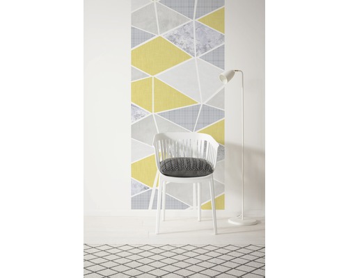 Papier peint décoratif à motif géométrique triangulaire, chaise blanche avec coussin et lampadaire sur un tapis à motifs.