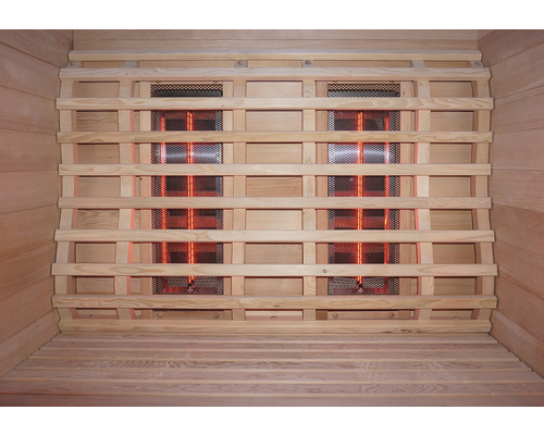 Vue intérieure d''un sauna infrarouge avec revêtement en bois et radiateurs infrarouges derrière une grille de protection.
