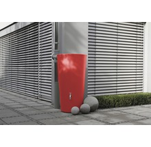 Récupérateur d''eau de pluie rouge avec robinet et trois boules de pierre dans le jardin