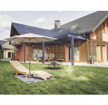 Jardin avec chaise longue, parasol, coin salon et foyer devant une maison.