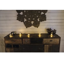 Commode avec tiroirs, décoration et guirlande lumineuse devant un mur en bois