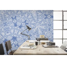 Arbeitszimmer mit blau gemusterter Tapete, Schreibtisch, Lampe und Stuhl