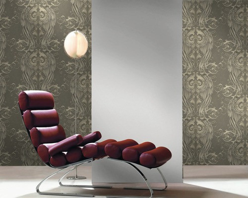 Dekorative Tapete mit geflügeltem Ornamentmuster in einem Interieur mit Sessel und Stehlampe.